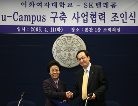 Shin Bae Kim, president of SK Telecom, and In-Ryung Shin, president of Ewha Womans University, are shown signing the MOU for building a u-Campus at Ewha Womans University